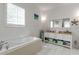 Bright bathroom featuring a soaking tub, tile floors, white cabinets, and neutral countertops at 402 Walls Way, Osprey, FL 34229