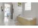 Bright bathroom featuring a soaking tub, white tile, and an open doorway to the bedroom at 402 Walls Way, Osprey, FL 34229