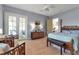 Bright bedroom with a cozy seating area, complemented by light wood floors and natural light from French doors at 402 Walls Way, Osprey, FL 34229