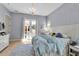 Sunlit bedroom with French doors to pool area, a chandelier, and light blue walls at 402 Walls Way, Osprey, FL 34229