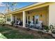 Covered patio with a hanging chair, rocking chairs, ceiling fan, and access to the landscaped backyard at 402 Walls Way, Osprey, FL 34229