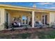 Relaxing covered patio includes a hanging chair, rocking chairs, ceiling fan, and access to the yard at 402 Walls Way, Osprey, FL 34229