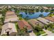 Aerial view of houses with tile roofs, surrounded by a serene lake and lush greenery in a well-planned community at 4134 63Rd E Ter, Sarasota, FL 34243