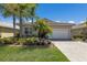Beautiful single-story home with a well-manicured lawn, palm trees, red tile roof, and a paved driveway leading to an attached garage at 4134 63Rd E Ter, Sarasota, FL 34243