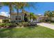 Charming single-story home featuring a red tile roof, lush landscaping, and a paved driveway leading to an attached garage at 4134 63Rd E Ter, Sarasota, FL 34243