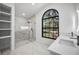 Bathroom featuring glass shower, arched window, and double sink with vanity and modern faucets at 4444 Robin Hood Trl W, Sarasota, FL 34232