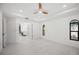 Bright bedroom with a ceiling fan, tray ceiling, white floors, windows, and an ensuite bathroom at 4444 Robin Hood Trl W, Sarasota, FL 34232