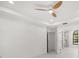 Bright white bedroom with a ceiling fan, white floor, view to ensuite bathroom and arched window at 4444 Robin Hood Trl W, Sarasota, FL 34232