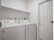 White laundry room with full sized washer and dryer and a built in shelf above at 4444 Robin Hood Trl W, Sarasota, FL 34232