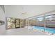 Indoor/outdoor pool area with ceiling fan, screened enclosure, and view of landscaping at 4444 Robin Hood Trl W, Sarasota, FL 34232