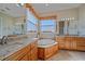 Inviting bathroom featuring dual sinks, wood cabinets, a soaking tub, and decorative accents for added luxury at 4510 Murcia Blvd # 16, Sarasota, FL 34238