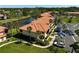 Aerial view of the condo community with red tile roofs and lush landscaping by a lake at 5201 Lake Village Dr # 14, Sarasota, FL 34235