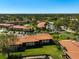 Aerial view of a community featuring lush landscaping, red tile roofs, and a serene pond at 5201 Lake Village Dr # 14, Sarasota, FL 34235