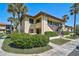 Exterior view of a two-story condo building with mature landscaping, stairs and an upper level balcony at 5201 Lake Village Dr # 14, Sarasota, FL 34235