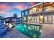 A luxury outdoor pool with fire bowls, reflecting the beautiful home at twilight at 606 Crestwood Ln, Holmes Beach, FL 34217