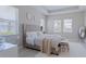 Bright bedroom showcasing a tufted headboard, white bedding, and a large window for ample natural light at 6172 Lungo Lago Dr, Sarasota, FL 34241