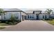 Beautiful home exterior with a brick driveway, manicured landscaping, and a three-car garage at 6172 Lungo Lago Dr, Sarasota, FL 34241