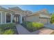 Charming home featuring a brick pathway, a three-car garage, and lush landscaping at 6915 Honeysuckle Trl, Lakewood Ranch, FL 34202