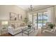 Elegant living room showcasing natural light, neutral decor, and sliding glass doors to the screened lanai and pool at 6915 Honeysuckle Trl, Lakewood Ranch, FL 34202
