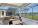 Screened patio with a lounge area overlooking a lush backyard and lake view at 6915 Honeysuckle Trl, Lakewood Ranch, FL 34202