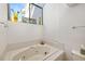 Bathroom with jacuzzi-style bathtub under a window, for spa-like relaxation at 7713 Fairway Woods Dr # 902, Sarasota, FL 34238