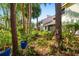 Home exterior with lush landscaping, mature trees, and potted plants for a tranquil backyard retreat at 7713 Fairway Woods Dr # 902, Sarasota, FL 34238