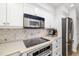Close-up of kitchen with white cabinets, stainless appliances, decorative backsplash and quartz countertops at 7713 Fairway Woods Dr # 902, Sarasota, FL 34238