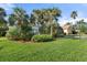 Lush front yard features mature landscaping with palm trees, shrubs, and verdant green grass at 826 Oak Briar Ln, Osprey, FL 34229