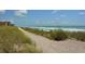 Beach view featuring sandy dunes, lush beach vegetation and gentle ocean waves at 8779 Midnight Pass Rd # 106H, Sarasota, FL 34242