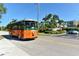 An orange trolley travels along a palm-lined street near local properties at 8779 Midnight Pass Rd # 106H, Sarasota, FL 34242