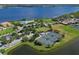 Aerial view showcasing community amenities including tennis courts, pool, and proximity to a large lake at 910 Tidewater Shores Loop # 107, Bradenton, FL 34208