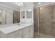 Modern bathroom featuring a quartz countertop, double mirrors, and a tiled shower with glass doors at 910 Tidewater Shores Loop # 107, Bradenton, FL 34208