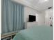 Comfortable bedroom boasting a TV, a 'Beach House' bench, and stylish blue curtains at 910 Tidewater Shores Loop # 107, Bradenton, FL 34208