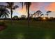 Scenic backyard view featuring a golf course, lush greenery, and a colorful sunset at 9408 Glen Abbey Ln, Sarasota, FL 34238