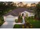 Aerial view of a home showcasing lush landscaping, a tiled roof, and an attached two-car garage at 9408 Glen Abbey Ln, Sarasota, FL 34238
