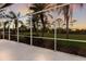 Screened-in lanai offering views of a golf course, palm trees, and a vibrant sunset at 9408 Glen Abbey Ln, Sarasota, FL 34238