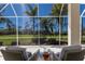 Relaxing screened-in lanai with wicker furniture overlooking the lush golf course at 9408 Glen Abbey Ln, Sarasota, FL 34238