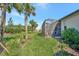 Well-maintained backyard featuring lush green grass, tropical landscaping, and a screened-in patio at 9928 Bright Water Dr, Englewood, FL 34223