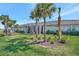 Backyard view featuring manicured lawn, tropical palm trees, and a screened lanai for outdoor enjoyment at 9928 Bright Water Dr, Englewood, FL 34223