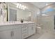 Bright bathroom features a double sink vanity, tile floors and a walk-in shower with glass door at 9928 Bright Water Dr, Englewood, FL 34223