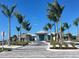 Well-maintained community entrance with elegant buildings, palm trees, and a paved driveway at 9928 Bright Water Dr, Englewood, FL 34223