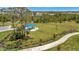 Aerial view of the fenced community dog park, featuring lush grass and shaded seating area and mature trees at 9928 Bright Water Dr, Englewood, FL 34223