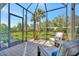 A covered lanai featuring comfortable seating and a serene view of the surrounding greenery at 9928 Bright Water Dr, Englewood, FL 34223