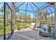 Screened lanai with brick flooring and seating offers peaceful outdoor living with views of lush landscaping at 9928 Bright Water Dr, Englewood, FL 34223