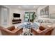 Bright living room featuring stylish decor, television, and sliding door to outdoor patio at 9928 Bright Water Dr, Englewood, FL 34223