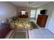 Comfortable bedroom with white tile floors, a leaf-patterned bedspread, wood furniture, and a bright window at 10522 Green Meadow Ln, Port Richey, FL 34668