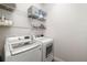 Functional laundry room with white washer and dryer, shelving, and ample storage space at 1216 Thornbury Dr, Parrish, FL 34219