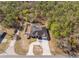 Aerial view of a home with a screened pool, a fenced yard, and surrounded by lush greenery at 13040 Quigley Ave, Weeki Wachee, FL 34614