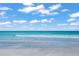 Calm beach view with the tide coming in, and crystal-clear ocean water under a blue sky and puffy clouds at 150 Medici Ter, North Venice, FL 34275