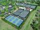 Aerial view featuring tennis and pickleball courts surrounded by well-manicured greenery and parking at 16407 Daysailor Trl, Lakewood Ranch, FL 34202